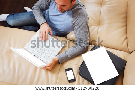 Man sitting using a modern laptop - clipping path for laptop screen, phone, and papers