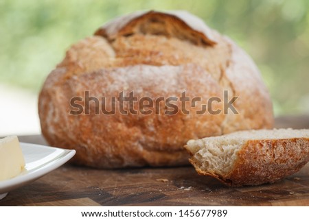 loaf of bread on cutting board. piece of bread with bite taken from it.