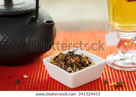 Loose leaf tea with tea pot and glass cup. Shallow depth of field. Focus on tea leaves