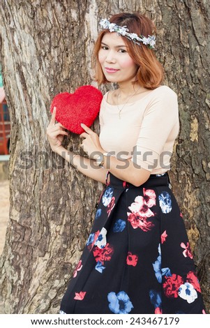 portrait of beautiful women asian posing under big tree and hand hold red heart cotton