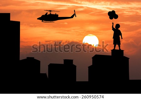 silhouette of high old building and the boy stand holding bubble look helicopter on sky sunset  background
