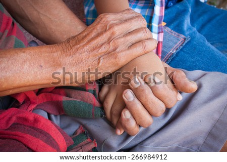 kids little  boy hand touches and holds an old man wrinkled hands.