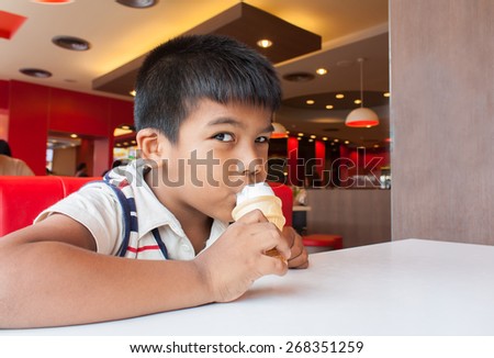 a young child\'s hand holding a dripping ice cream cone in shop