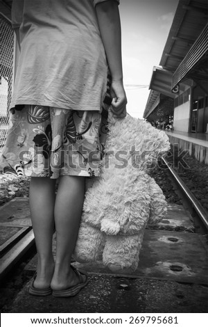 black and white tone girl standing alone and hand hold white bear at Railway Platform