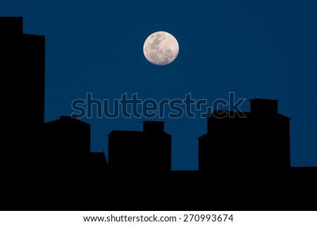 silhouette of full moon over some of high old building