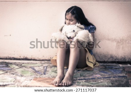 Blurry sad asian girl alone sitting with white bear near old wall cement,vintage tone