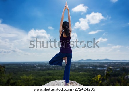 young woman practicing yoga on landscape town and sea