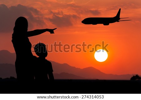 Mother  hugging her son  use hand point airplane on the sky at sunset