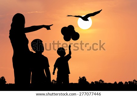 silhouette of mother hugging her son use hand point eagle fly on the sky at sunset