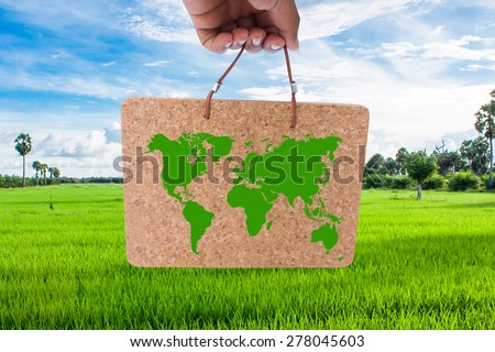 concept save the world - hand holding board of the world map on green cornfield and blue sky