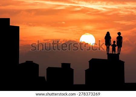 silhouette of high old building and the three child  standing and looking forward on sky sunset background