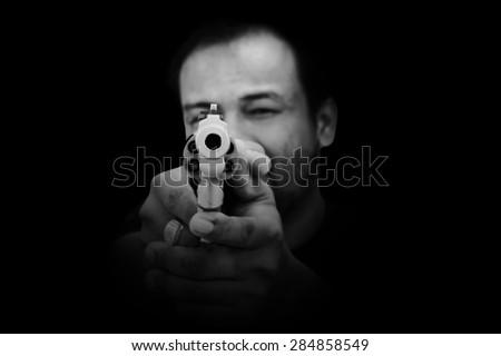 black and white of  man holding gun and pointing his gun revolver. Selectively concentrated on the front of the gun.