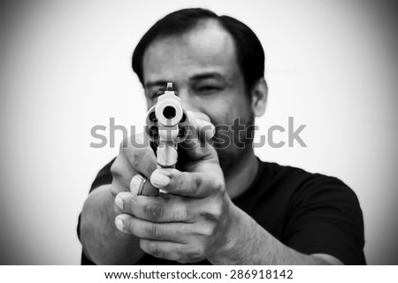 black and white of man holding gun and pointing his gun revolver. Selectively concentrated on the front of the gun.