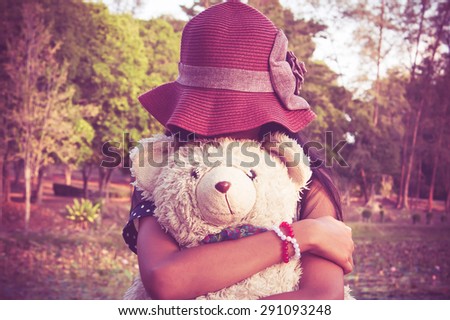 asian cute girl standing alone at the lagoon and hand bear hug,vintage tone