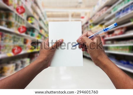 hand women shopping and  holding empty notebook for check list her buy in the supermarket
