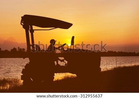 silhouette of asian little boy driver tractor on river sunset background