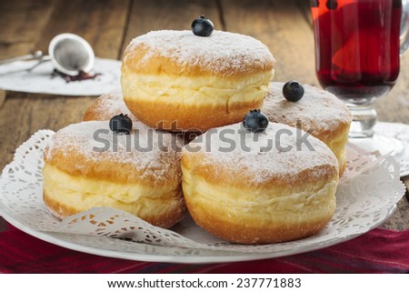 Sugary donuts and hibiscus red tea on a wooden background.