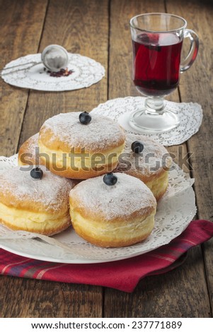 Sugary donuts and hibiscus red tea on a wooden background.
