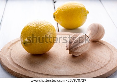 Wooden citrus squeezer,  half of a lemon and juice on light background