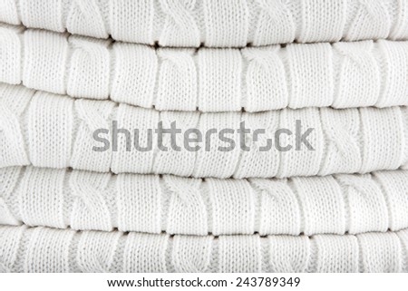 Close up of folded white knitted  plaid. Knitted fabric texture. Background.