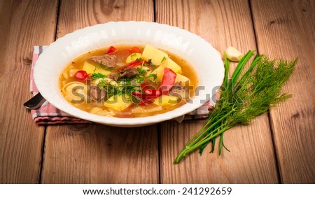 Traditional hungarian hot soup on the wooden background.
