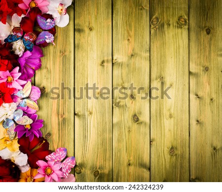 Spring decor -artificial flowers and butterflies on the wooden background.