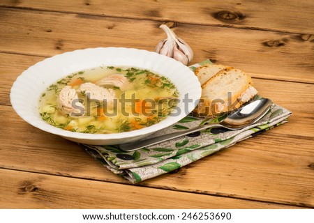 Chicken soup with a bread and garlic on the wooden background.