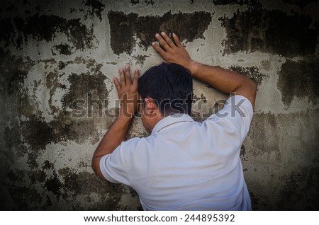 Young desperate man who lost job abandoned and against brick wall