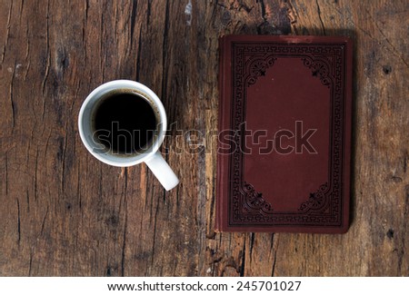 Cup of coffee and old book on old wooden table