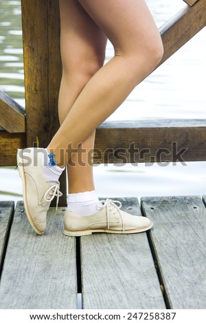Female legs on the wooden floor by the lake