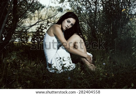 Pale woman in white dress on the ground, dark mystery scene