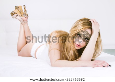 Sexy woman in white underwear and with mask on the bed