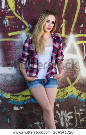 Trendy hipster girl standing next to graffiti wall