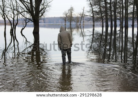 Man in jacket and military pants standing in the water in autumn. Lonjsko polje, Croatia.