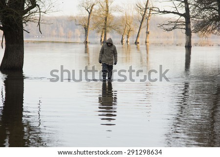 Man in jacket and military pants standing in the water in autumn. Lonjsko polje, Croatia.