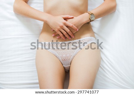 Sexy girl in white lace panties lying on the bed, hands on belly, body detail