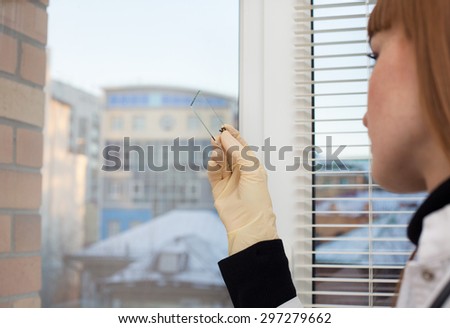 female doctor examining a slide standing by a window