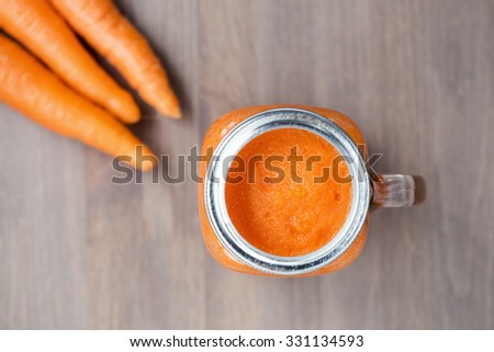 Healthy carrot smoothie in a jar with carrots on wooden background. Shallow dof