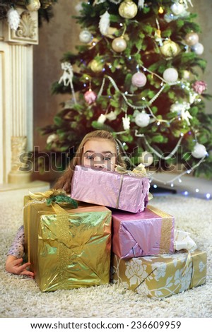 little girl and a pile of gifts near Christmas tree