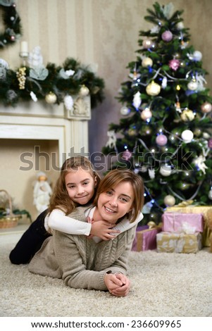 mother and daughter near Christmas tree and gifts. Family holiday