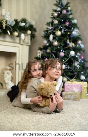 mother and daughter are dreaming near Christmas tree. Family holiday