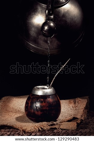 Pouring hot water from kettle into the calabash