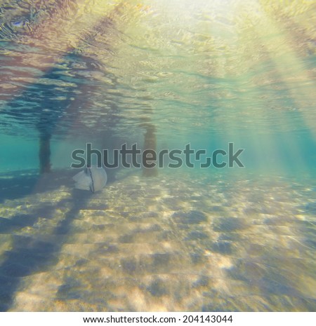 Underwater ripples of sunlight reflected on a sandy sea floor