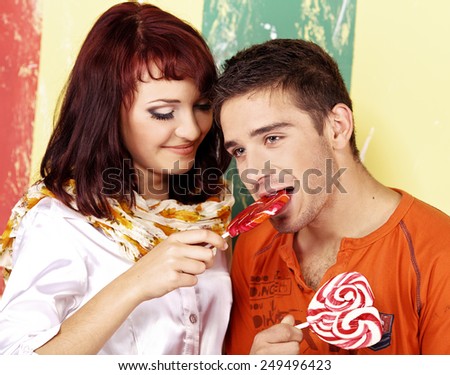 happy young couple eating candy lollipop together