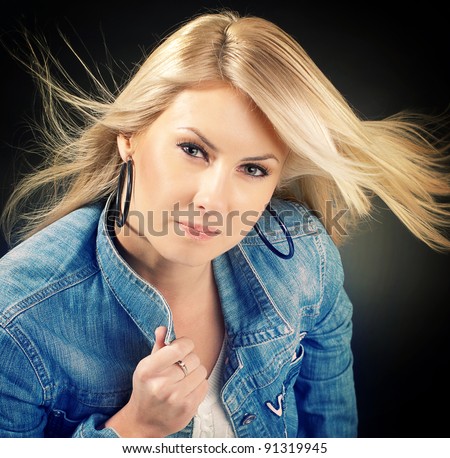 young woman dressed in jean jacket holding on herself jacket collar