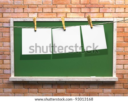 Hanging blank paper on clothesline and green blackboard with wooden frame on brick wall