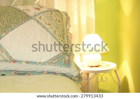 Romantic pillow in a shabby chic bedroom with green walls. Close-up, selective focus.