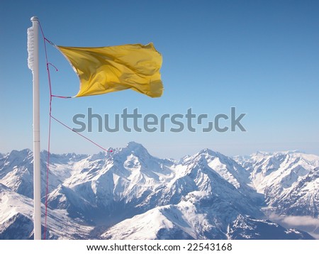 The yellow flapping flag over snow-covered Alps.