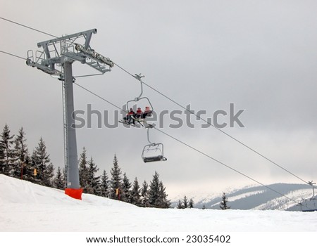 Skiers on the ski lift chair, carry high up on mountains.