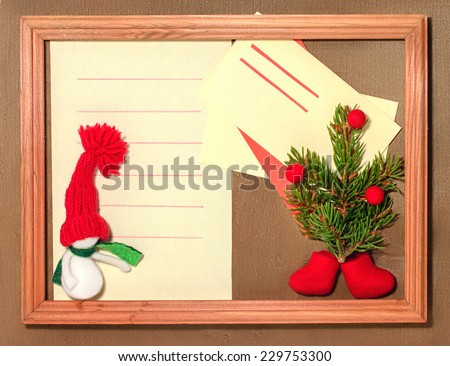 Blank sheet, envelope, snowmen and Christmas tree with boots in a frame on the wooden background.